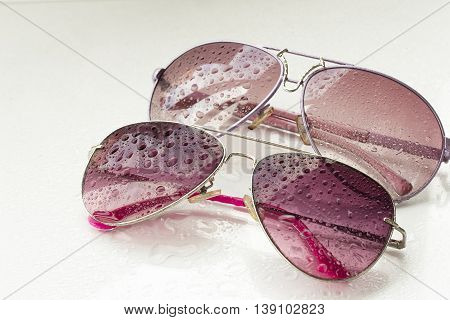 pink sunglasses and drops on an isolated white background
