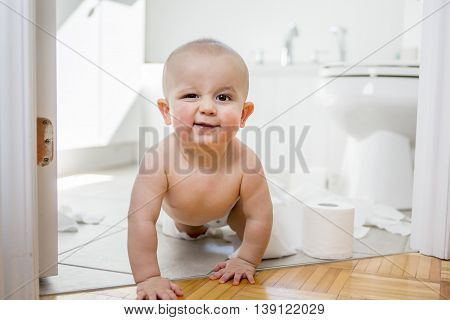 An Adorable baby boy playing with toilet paper