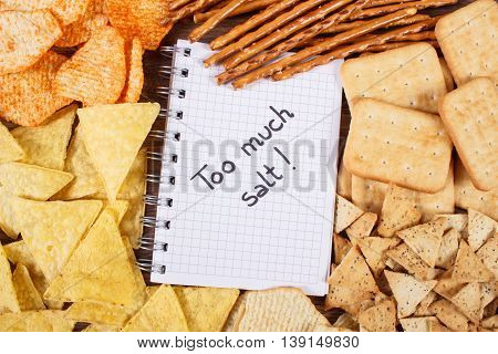 Inscription Too Much Salt In Notebook And Heap Of Unhealthy Food