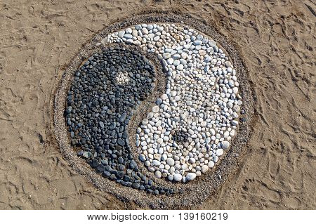 The conception of yin and yang is laid with stones on the sandYin and yang of stones