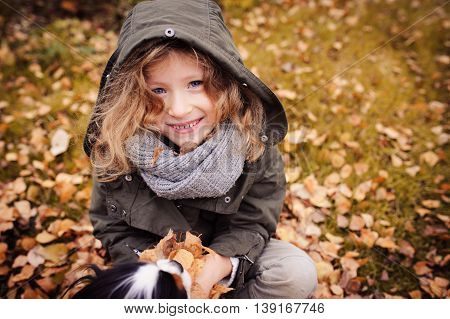 happy child playing with leaves in autumn. Seasonal outdoor activities with kids. Lifestyle capture on the walk.
