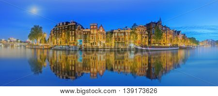 Amstel river, canals and night view of beautiful Amsterdam city. Netherlands.