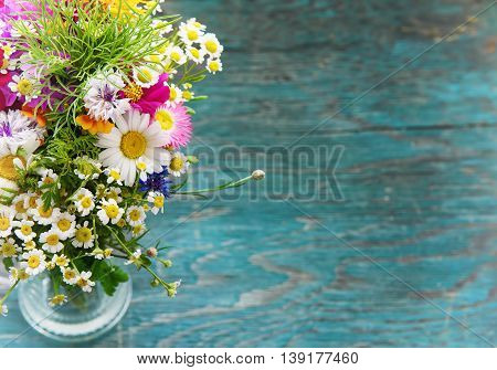 Bouquet of fresh summer flowers on the blue wooden grunge desk. Mock up for greeting cards, holiday postcards, invintation and anniversary celebration in vintage hipster style with copy space