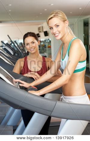 Frau mit weiblichen Personal Trainer zum Ausführen von Maschine In Turnhalle
