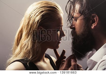 young sexy couple of pretty woman with blonde hair and handsome bearded man with long beard embracing on grey background