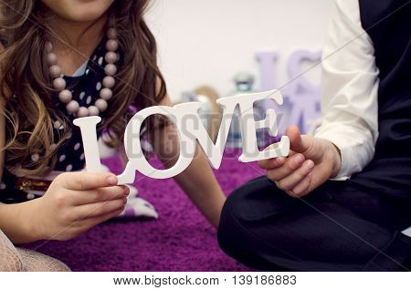 Image of boy and girl holding wooden inscription love