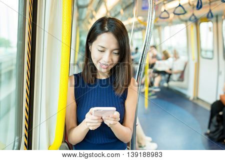 Woman sending sms on cellphone inside MTR in Hong Kong