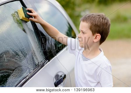 Little Boy Washing Silver Car In The Garden