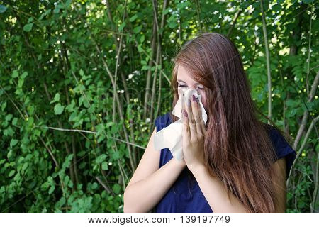 young woman blowing her nose with paper tissue