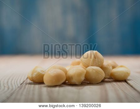 Macadamia on wooden floor with blue wooden background blur.Focus on macadamia.
