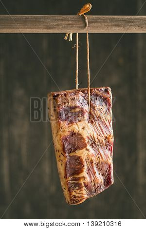 Fresh smooked bacon hanging on wooden stick.
