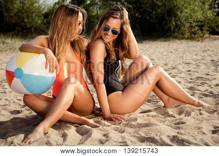 healthy young woman laughing with beachball while on the beach in summer