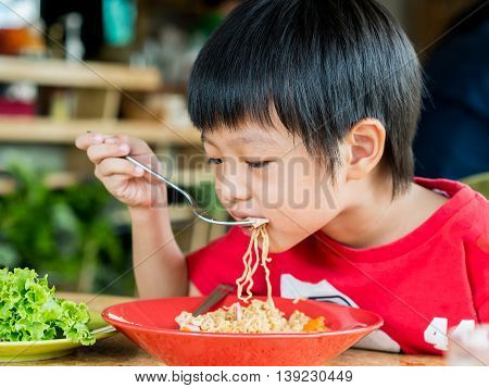 Happy Asian cute boy eating delicious noodle
