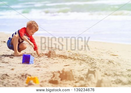 little boy play with sand on summer tropical beach