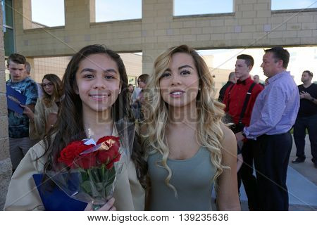 JOLIET, ILLINOIS / UNITED STATES - MAY 19, 2015: A girl proudly holds her diploma, and a bouquet of red roses, after an eighth grade graduation ceremony held at Plainfield South High School.