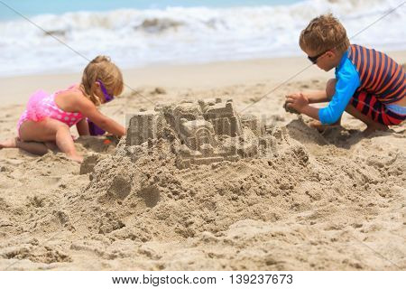 little boy and girl building sand castle on summer beach
