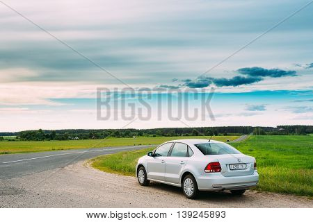 Gomel, Belarus - June 13, 2016: Volkswagen Polo Car Parking On A Roadside Of Country Road On A Background Of Green Spring Fields Or Meadow In Sunny Day With A Beautiful Blue Sky