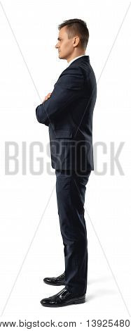 Side view of a young businessman with his arms folded looking staight confidently isolated on a white background. Self-assured man. Office clothes. Successful look. Presentable outfit. Dress code.