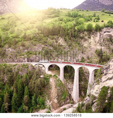 Passenger train goes from St. Moritz to Chur on Landwasser viaduct.