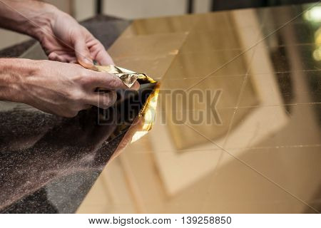 Master works with a thin gold leaf pieces on glass hands in the center of the frame