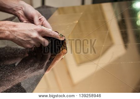 Master works with a thin gold leaf pieces on glass hands in the center of the frame