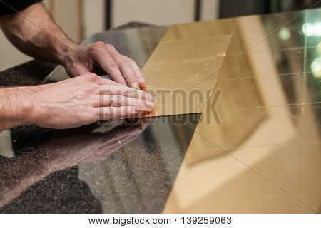 Master works with a thin gold leaf pieces on glass hands in the center of the frame