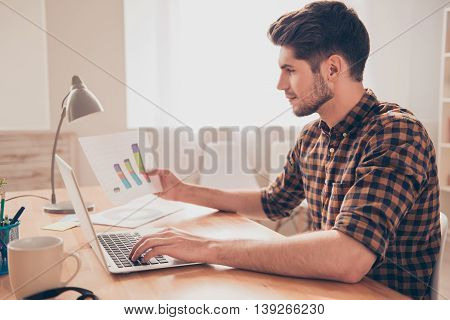 Side View Of Concentrated Young Man Working With Laptop And Diagrama