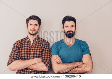 two handsome serious men cross hands while standing gray background