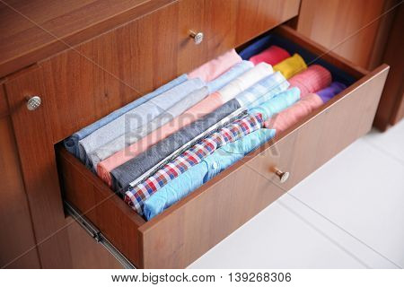 Neatly folded clothes in wooden drawer
