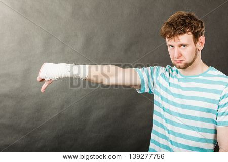 Sad Man Showing Thumb Down By Bandaged Hand.