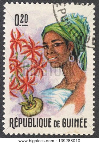 MOSCOW RUSSIA - CIRCA JANUARY 2016: a stamp printed in GUINEA shows a woman in the traditional headdress and a plant Haemanthus sp. the series 
