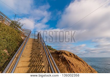 Staircase at Ladera Street going up a cliff with a cloudy sky background at Sunset Cliffs in San Diego, California.