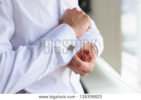 Male buttons cufflinks. Businessman buttons cufflinks in white shirt. Groom in morning wears shirt to a wedding.