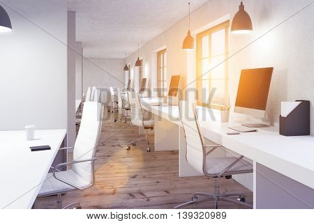 Coworking office interior with wooden floor white desks blank computer monitors and window with city view and sunlilght. Toned image 3D Rendering