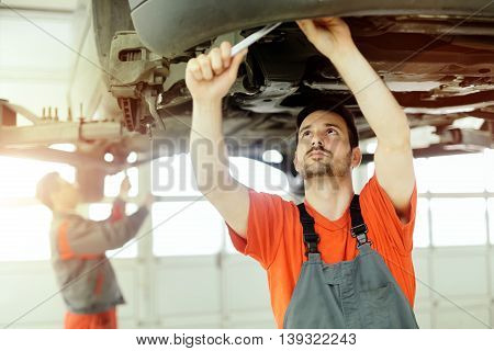 Car mechanic upkeeping car in dealership garage