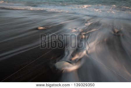 Pebbles in the beach with flowing sea water creating nice textures