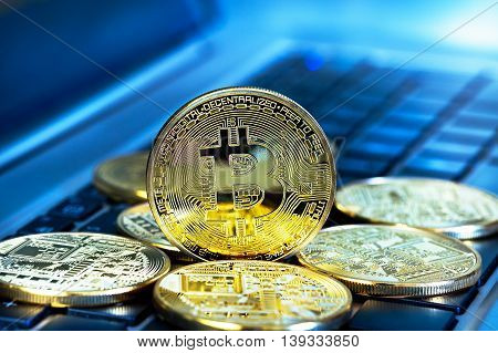 Photo Golden Bitcoins (new virtual money ) close-up on a blue background with a computer keyboard.