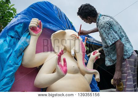 KOLKATA WEST BENGAL INDIA - 13 SEPTEMBER 2015: An unidentified artist paints a clay idol of Lord Ganesha as preparation for 
