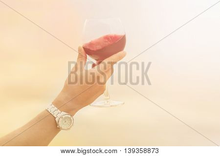 Toned picture of glass with old red wine in sommelier's hand. Red wine is tasted by sommelier isolated on blue sky background.
