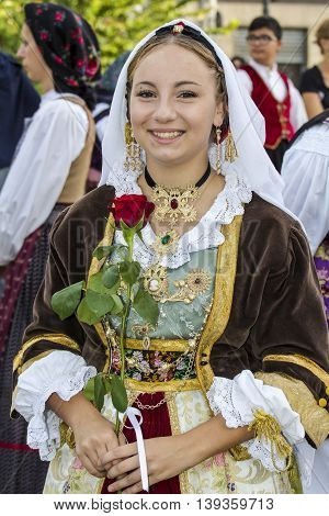 SELARGIUS, ITALY - September 13, 2015: Former marriage Selargino - Sardinia - portrait of a beautiful smiling girl in Sardinian costume holding a rose in hand