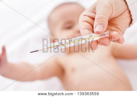 Beby and temperature hand holding thermometer, close up