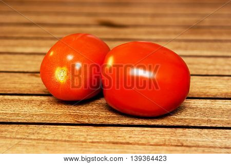 Two Delicius Tomatoes on a wood table.