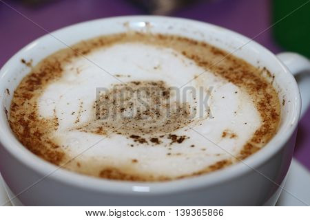 Freshly brewed cappuccino, with a decorative pattern on the foam heart