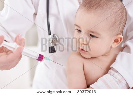 Female doctor does injection child vaccination, close up