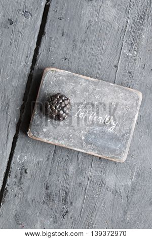 Eat heathy inscription and blackberries on a wooden table.