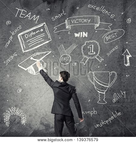 Rear view of man drawing education concept on blackboard with chalk