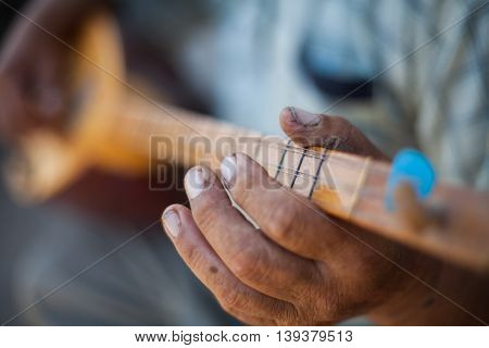 Close up shot of a man playing a Tatar instrument called 