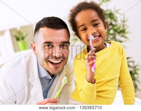 Beautiful Girl And Pediatrician Brushing Teeth Together