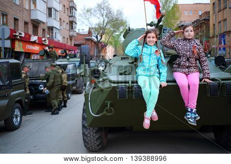 SAMARA - MAY, 6, 2015: Two girls (with model releases) pose on armored vehicle in Samara during military celebration. Red Square is not affected by military equipment on parade May 9th