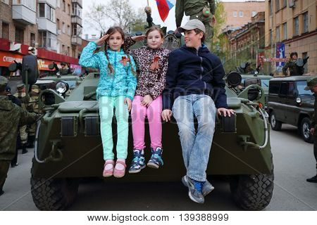 SAMARA - MAY, 6, 2015: Boy and two girls (with model releases) sitting on armored vehicle in Samara during military celebration. Red Square is not affected by military equipment on parade May 9th